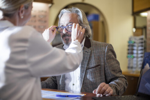 Optiker hilft Kunden bei der Auswahl einer neuen Brille - ZEF10402
