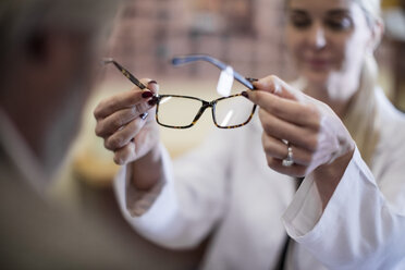 Optician helping customer to choose new spectacles - ZEF10403