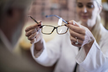Optiker hilft Kunden bei der Auswahl einer neuen Brille - ZEF10403