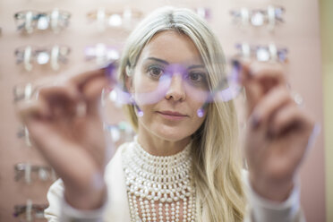 Blond woman selecting new glasses in opticians shop - ZEF10410