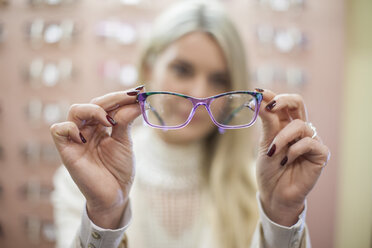 Blonde Frau wählt in einem Optikergeschäft eine neue Brille aus - ZEF10411