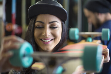 Junge Frau begutachtet Skateboard in einem Geschäft - ZEF10444