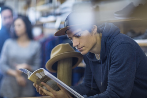 Junger Mann im Laden, der eine Zeitschrift liest, lizenzfreies Stockfoto