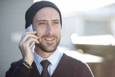 Junger Mann mit Mütze, der mit einem Handy telefoniert - ZEF10475