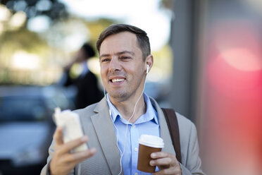 Businessman with cell phone listening to music - ZEF10476