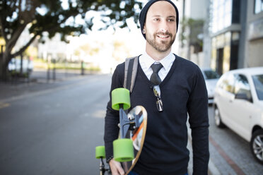 Young man wearing beanie holding skateboard - ZEF10493