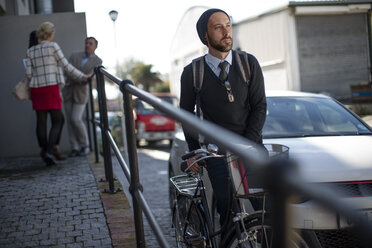 Man pushing bicycle on city street - ZEF10496