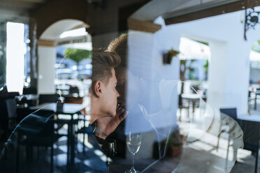 Young couple kissing in a bar seen from behind window - KIJF00833