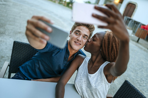 Junges Paar macht Selfies in einem Straßencafé, lizenzfreies Stockfoto