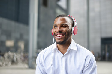 Portait of happy businessman listening music with headphones - DIGF01330