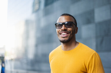 Porträt eines lächelnden Mannes mit gelbem Pullover und Sonnenbrille - DIGF01344