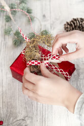 Hände eines Mädchens beim Einpacken eines Weihnachtsgeschenks - SARF02956