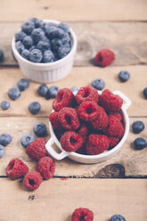 Bowls of raspberries and blueberries on wood - RTBF00414