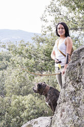 Porträt einer lächelnden Bogenschützin mit ihrem Hund in der Natur - ABZF01318
