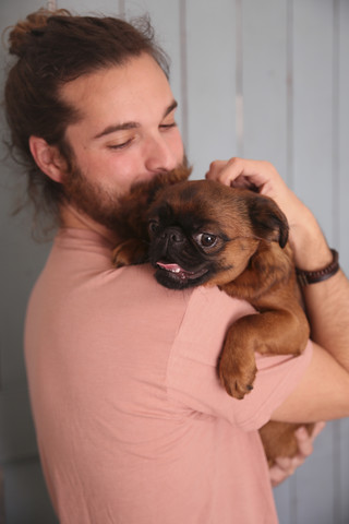 Mann hält Petit Brabancon auf seinem Arm, lizenzfreies Stockfoto