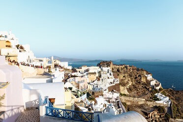 Griechenland, Santorini, Oia, Blick auf das Dorf in der Abenddämmerung mit Touristen, die auf den Sonnenuntergang warten - GEMF01086