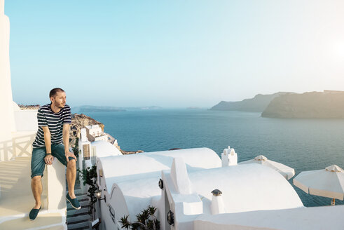 Griechenland, Santorini, Oia, Mann sitzt auf einer Mauer und genießt den Sonnenuntergang - GEMF01089