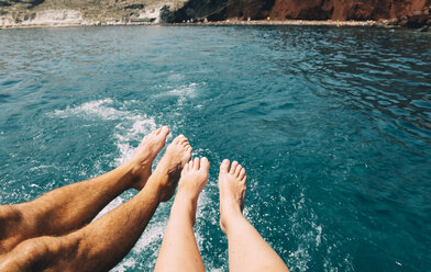 Greece, Santorini, legs of a couple in front of the sea - GEMF01102