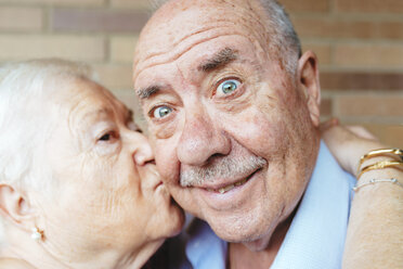 Senior man pulling funny face while his wife kissing him - GEMF01105