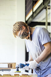 Man sanding wood with a random orbital sander - KNTF00523