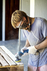 Man sanding pallet with a random orbital sander - KNTF00525