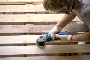 Man sanding pallet with a random orbital sander - KNTF00533