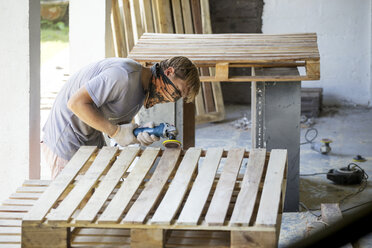 Man sanding pallet with a random orbital sander - KNTF00534