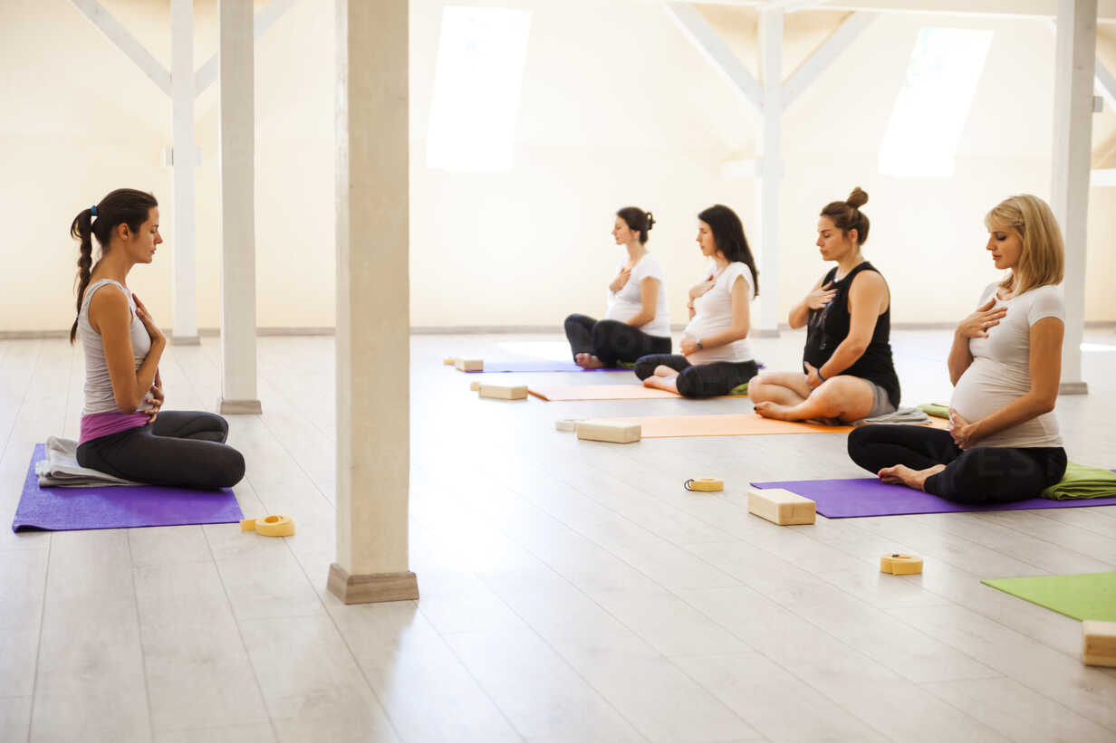 Pregnant woman in her third trimester practices prenatal yoga in a