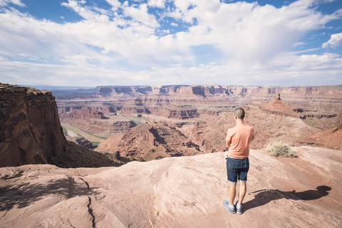 USA, Utah, Junger Mann steht am Dead Horse Point und schaut zum Colorado River, lizenzfreies Stockfoto