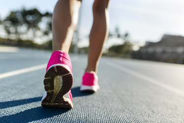 Legs of female athlete running on racetrack - MGOF02469