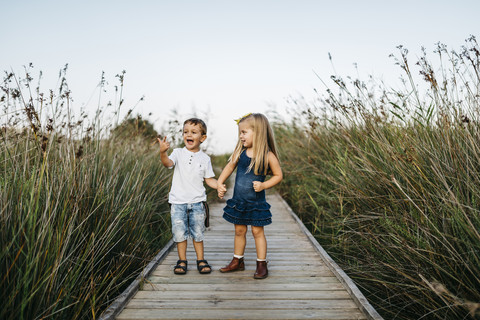 Two little children playing together on boardwalk in nature stock photo