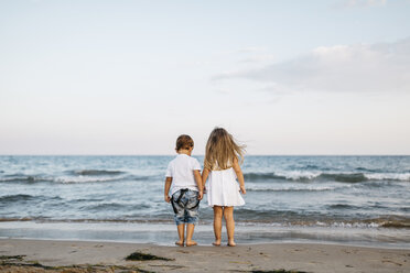 Rückenansicht eines kleinen Jungen und eines Mädchens, die Seite an Seite am Meer stehen - JRFF00882