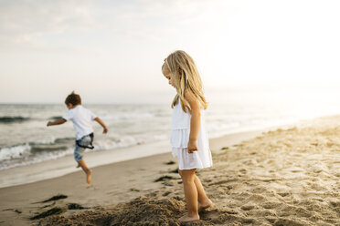 Little boy and girl playing on the beach - JRFF00883