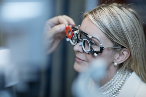 Optometristin beim Einstellen der Testfassung für den Patienten, lizenzfreies Stockfoto