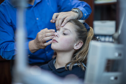 Optometrist inserting contact lens into girl's eye - ZEF10594