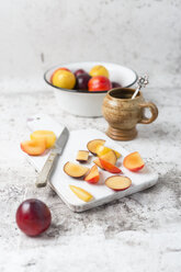 Various plums in bowl, chopping board with knife - MYF01789