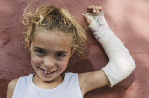 Porträt eines lächelnden blonden Mädchens mit eingegipstem Arm - RAEF01504