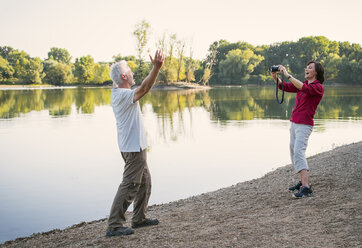 Glückliches Seniorenpaar an einem See beim Fotografieren - ONF01029