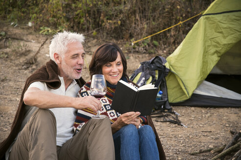Glückliches Seniorenpaar mit Wein und Buch in einem Zelt - ONF01038