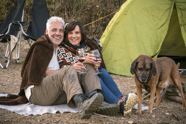 Happy senior couple with wine and dog at a tent - ONF01039