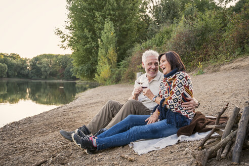 Glückliches älteres Paar mit Wein an einem See am Abend - ONF01040