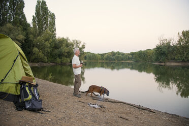 Älterer Mann mit Hund beim Zelten an einem See - ONF01051