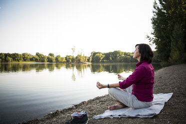 Senior woman at a lake practicing yoga - ONF01069