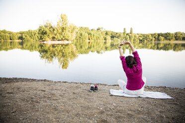 Senior woman stretching at a lake - ONF01070