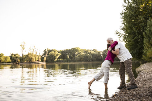 Älteres Paar umarmt sich an einem See - ONF01072