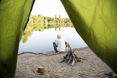 Älterer Mann mit Hund beim Zelten an einem See - ONF01076