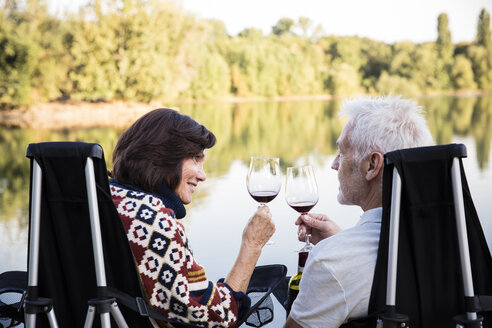 Älteres Paar stößt abends an einem See mit Weingläsern an - ONF01085