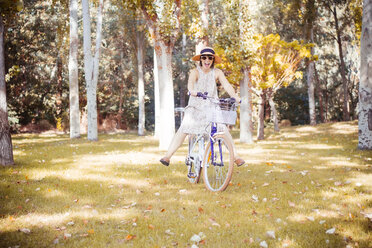 Frau balanciert auf einem Fahrrad in einem herbstlichen Park - JPSF00017