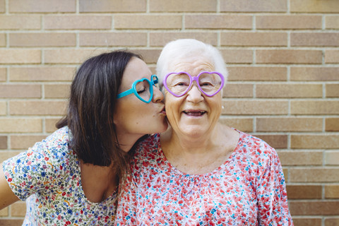 Glückliche Enkelin und Großmutter mit herzförmiger Brille, lizenzfreies Stockfoto