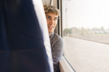 Young man sitting in a train looking through window - FMOF00134